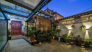 A courtyard with a glass enclosure, potted plants, and a traditional door.