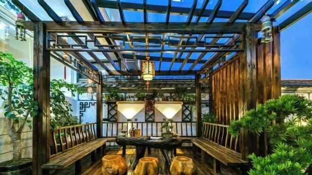 A wooden pergola with a table and benches, surrounded by potted plants. - Dali Yunpingrui Boutique Homestay (Dali City)
