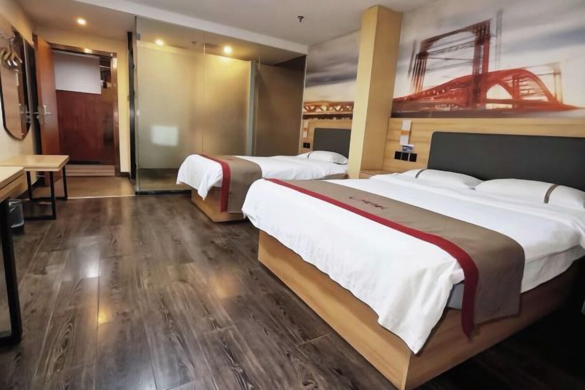 A hotel room with two beds, a desk, and a view of a bridge.