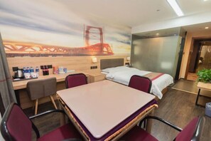 A hotel room with a bed, a desk, a chair, a table, and a mural of a bridge. - Shankee Hotel (Anqing Qijie Railway Station) (Anqing)