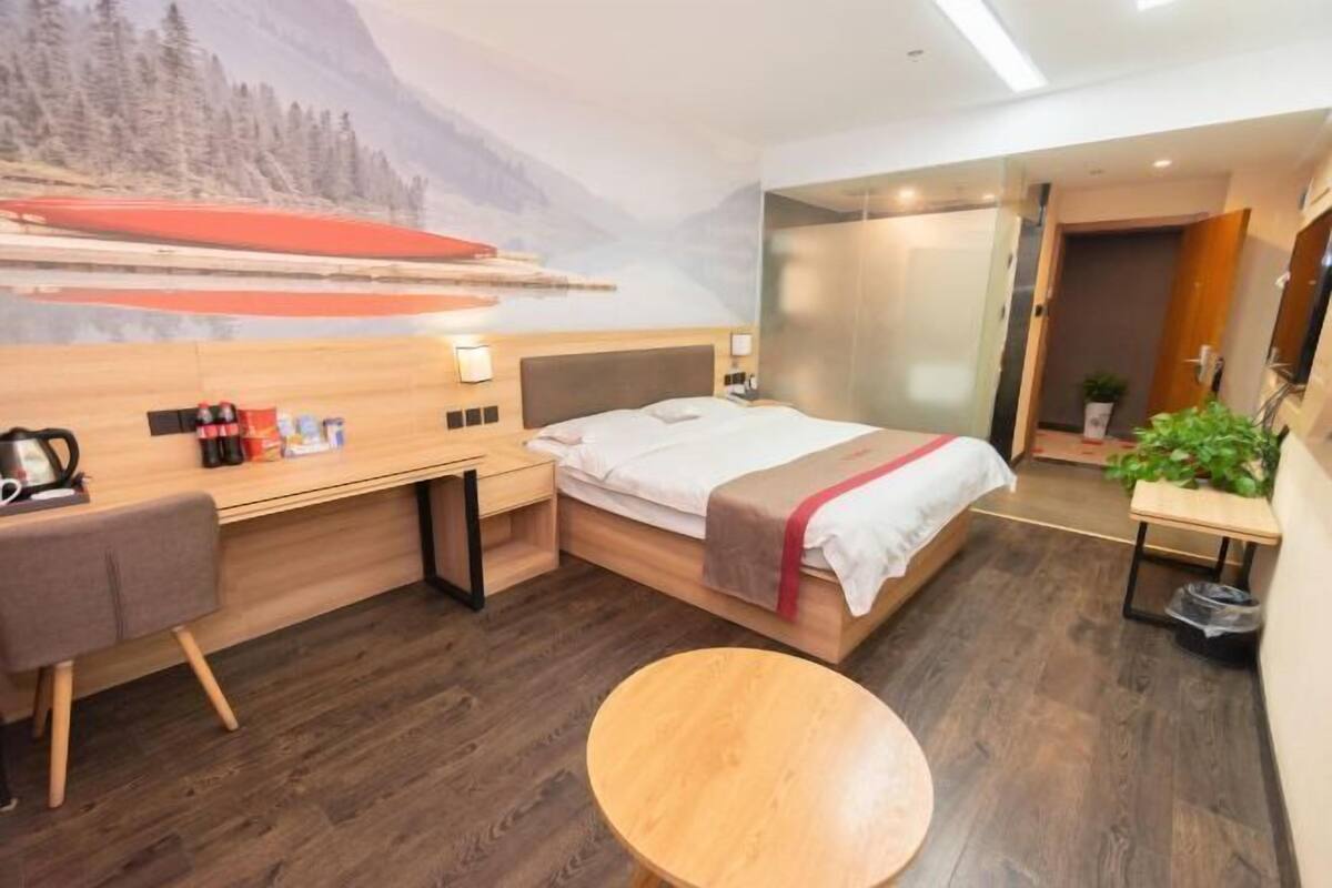 A modern hotel room with a bed, desk, chair, and round table.