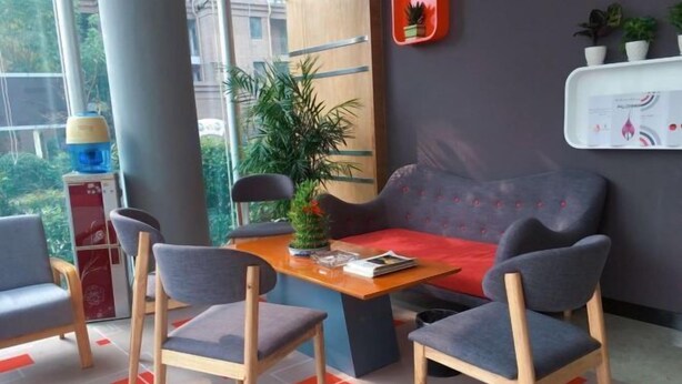 Un área de espera moderna con un sofá, dos sillones, una mesa y una planta en maceta.
