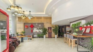 Una zona de recepción moderna con techo curvo, detalles de madera y varias áreas de descanso.