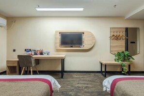 A hotel room with two beds, a desk, a TV mounted on the wall, a mirror, and a plant. - Shankee Hotel (Anqing Qijie Railway Station) (Anqing)