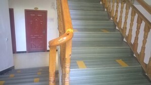 A staircase with a wooden handrail and a red door at the top.