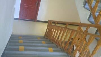 A staircase with wooden handrails and a red door at the top.