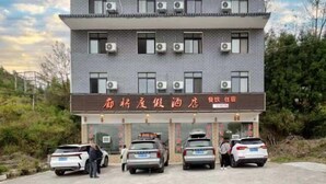 A multi-story building with air conditioning units, a signboard, and parked cars.