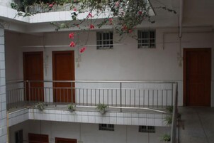 Un edificio de varios niveles con balcones, puertas de madera y macetas con plantas.
