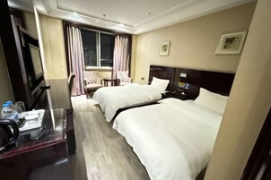 Habitación de hotel con dos camas, un escritorio con silla, televisión y ventana con cortinas.