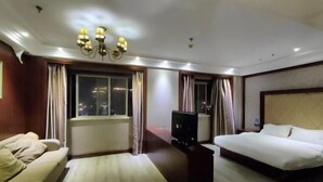 Une chambre d’hôtel avec un lit, un canapé, une télévision et une fenêtre avec des rideaux.