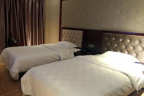 Une chambre d’hôtel avec deux lits, une tête de lit et un rideau.