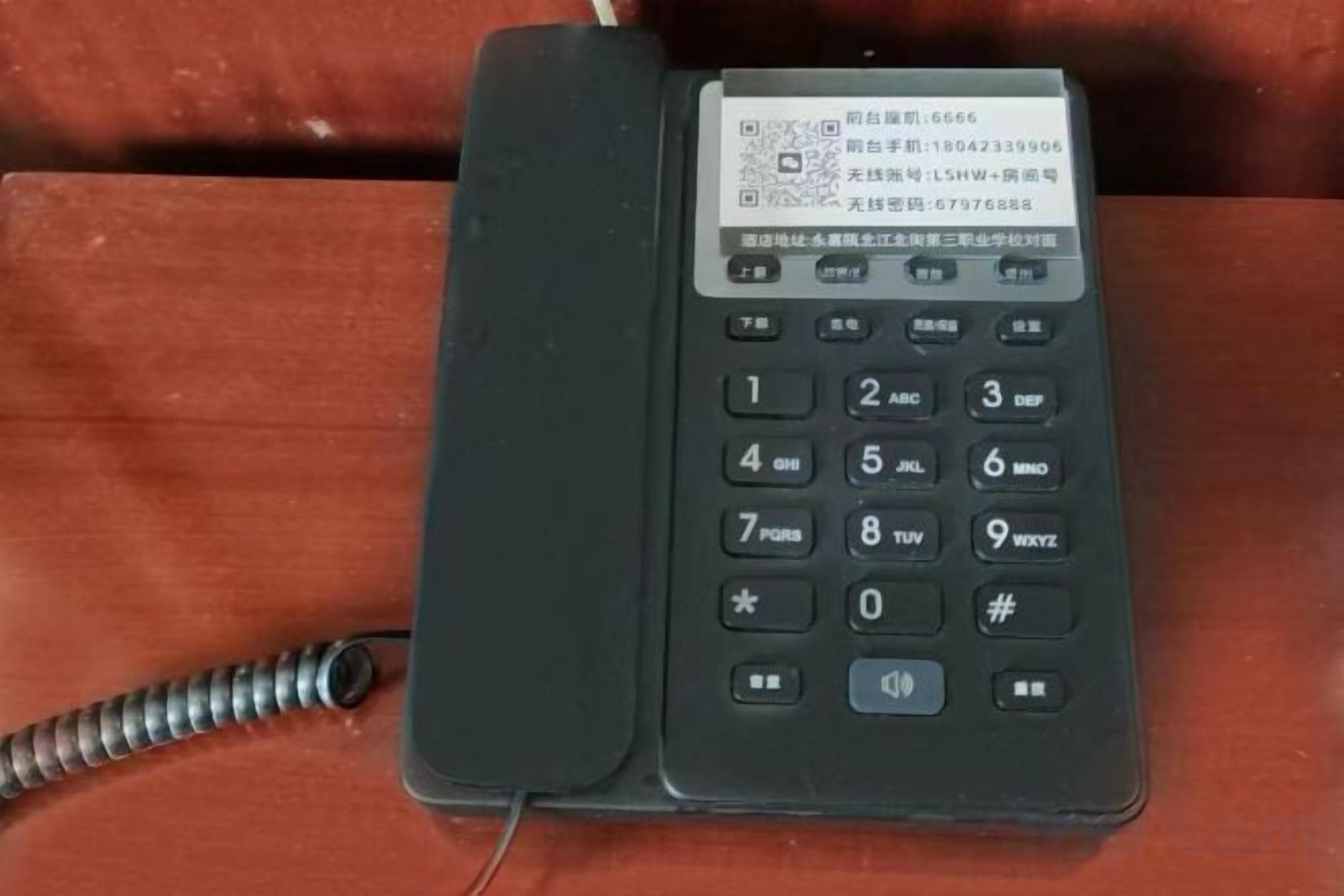 A black telephone with a label on the top.