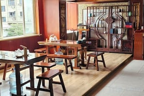 A traditional wooden interior with tables and benches, a window with a view, and a decorative wooden screen. - Lanse Haiwan International Hotel (Yongjia)