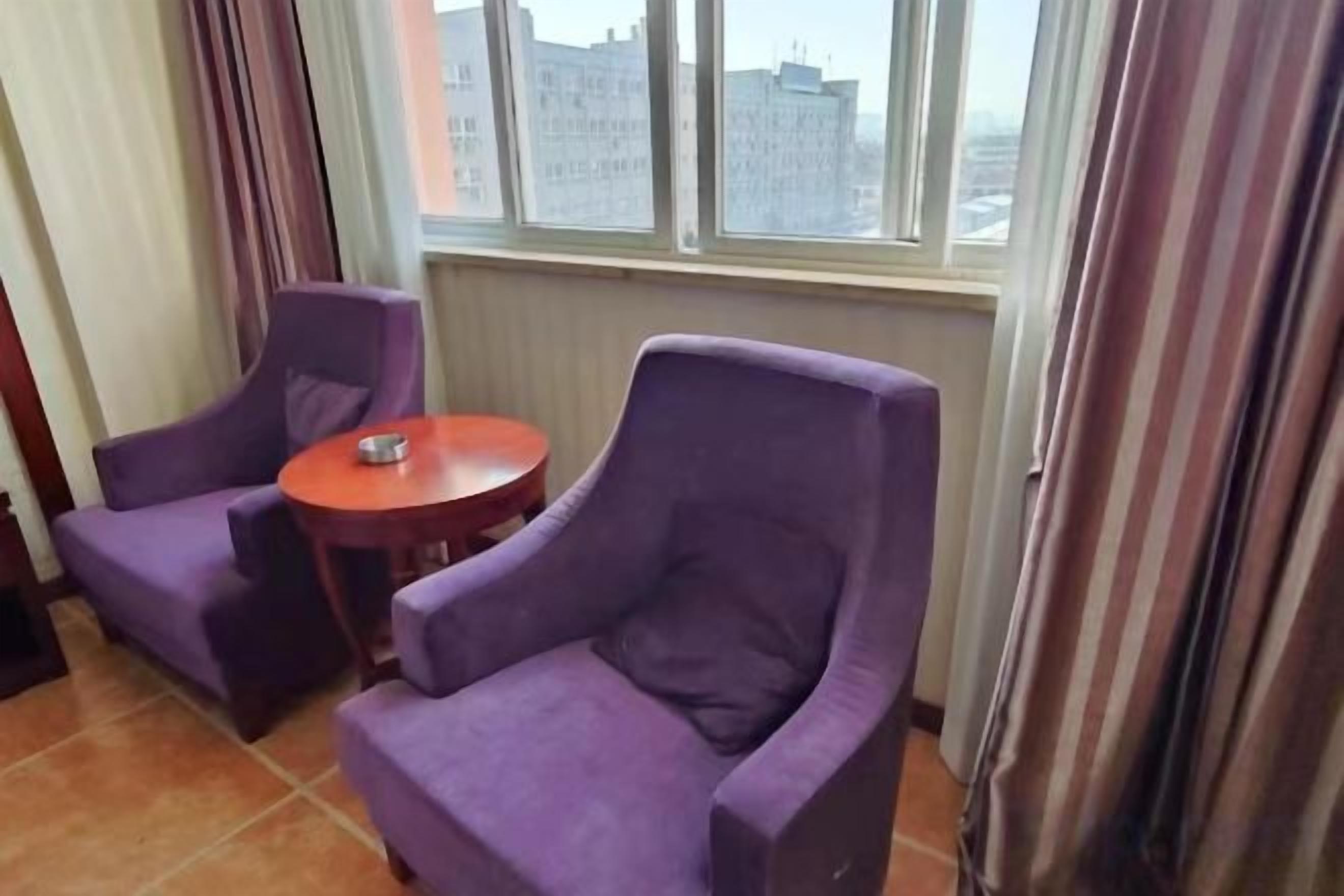 A room with two purple armchairs and a small round table.