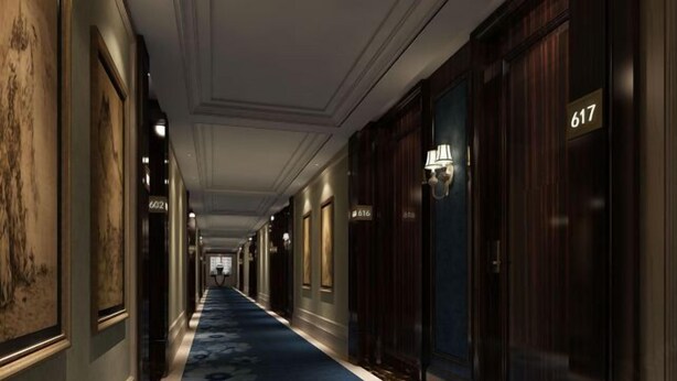 Un couloir d’hôtel avec un tapis bleu, des portes en bois et des panneaux indiquant le numéro des chambres.