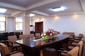 Una sala de conferències amb una taula oval gran, nombroses cadires i un arranjament floral.