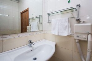 Un baño con lavamanos, espejo, toallero y secador de pelo.