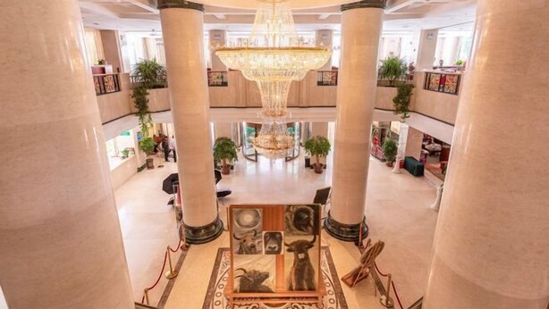 A grand lobby with a large chandelier, marble columns, and artwork on the walls. - Himalaya Lhasa Hotel (Lhasa)