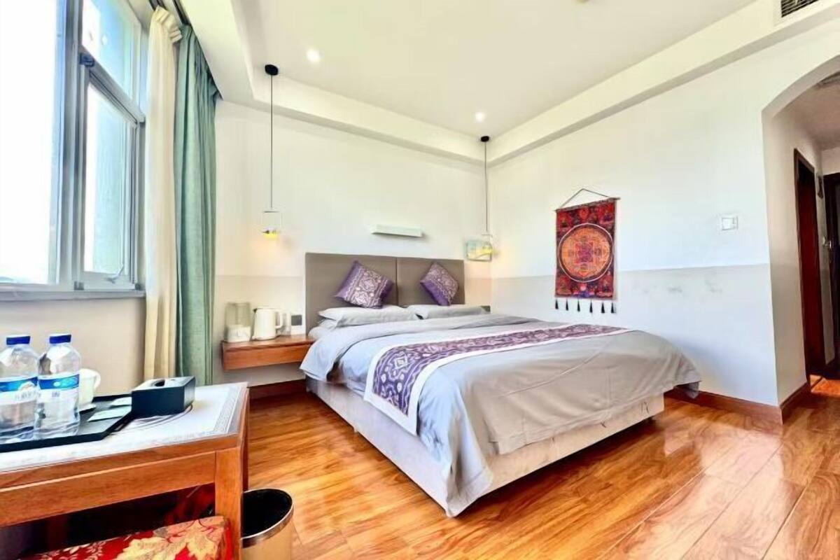 A hotel room with a bed, bedside table, and a window with curtains.