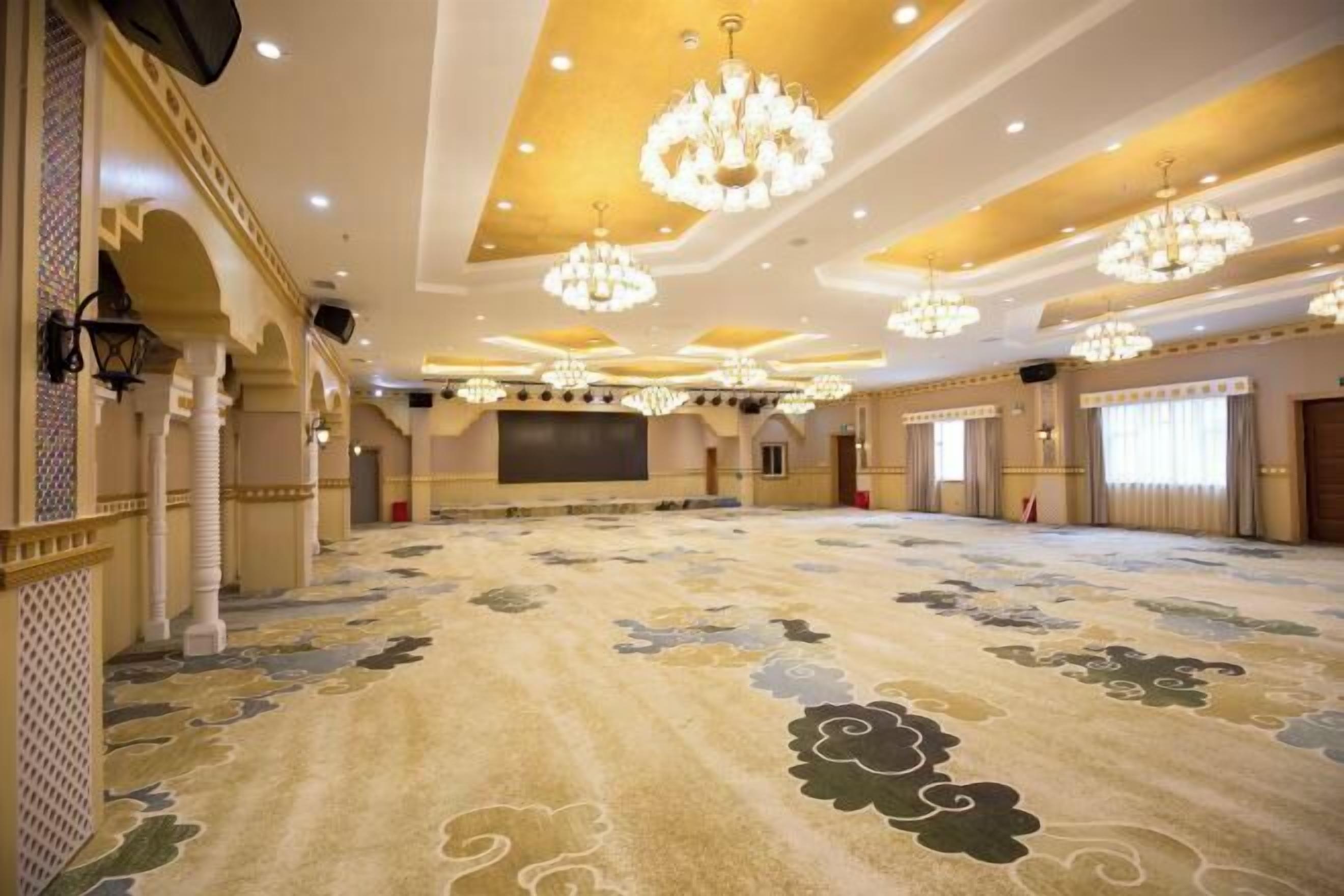 A spacious hall with ornate chandeliers, patterned carpet, and traditional architectural elements.