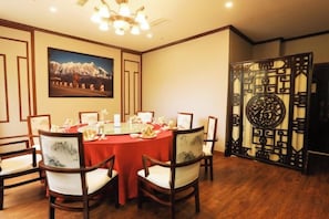 A dining area with a round table, chairs, and a decorative screen. - Himalaya Lhasa Hotel (Lhasa)