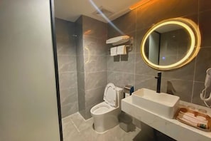 Un baño moderno con inodoro, lavamanos y espejo.