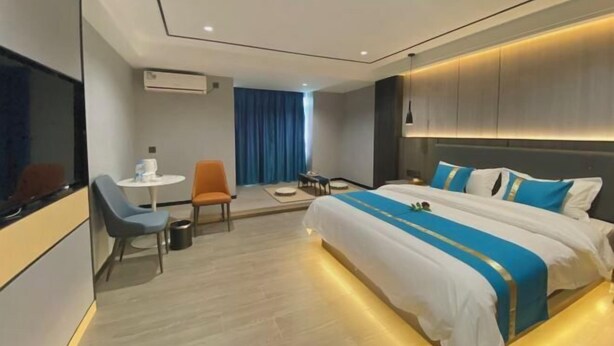 Une chambre d’hôtel moderne avec un grand lit, une petite table, deux chaises et un téléviseur.