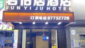La façade de l’hôtel Junyijuhu, avec une enseigne bien visible indiquant le nom de l’établissement et un numéro de téléphone.