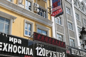 A building with multiple signs, including one for 'ИРА ЭКСНОСИЛА' and another for '120РУБЛЕЙ'.