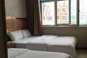 Una habitación de hotel con dos camas, una ventana con vistas a edificios y un cabecero de madera.