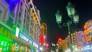 A brightly lit street with illuminated signs and traditional street lamps. - Hui Zi Inn (Manzhouli)