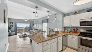 Una cocina moderna con encimeras de granito, electrodomésticos de acero inoxidable y armarios blancos.