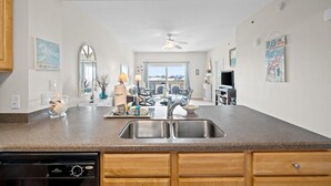 Una cocina moderna con encimeras de granito, pileta doble, muebles de madera y vista al área de comedor.