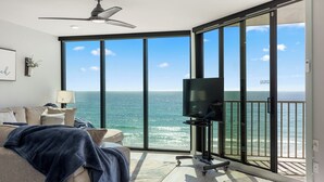 A modern room with a large sliding glass door leading to a balcony with ocean views.