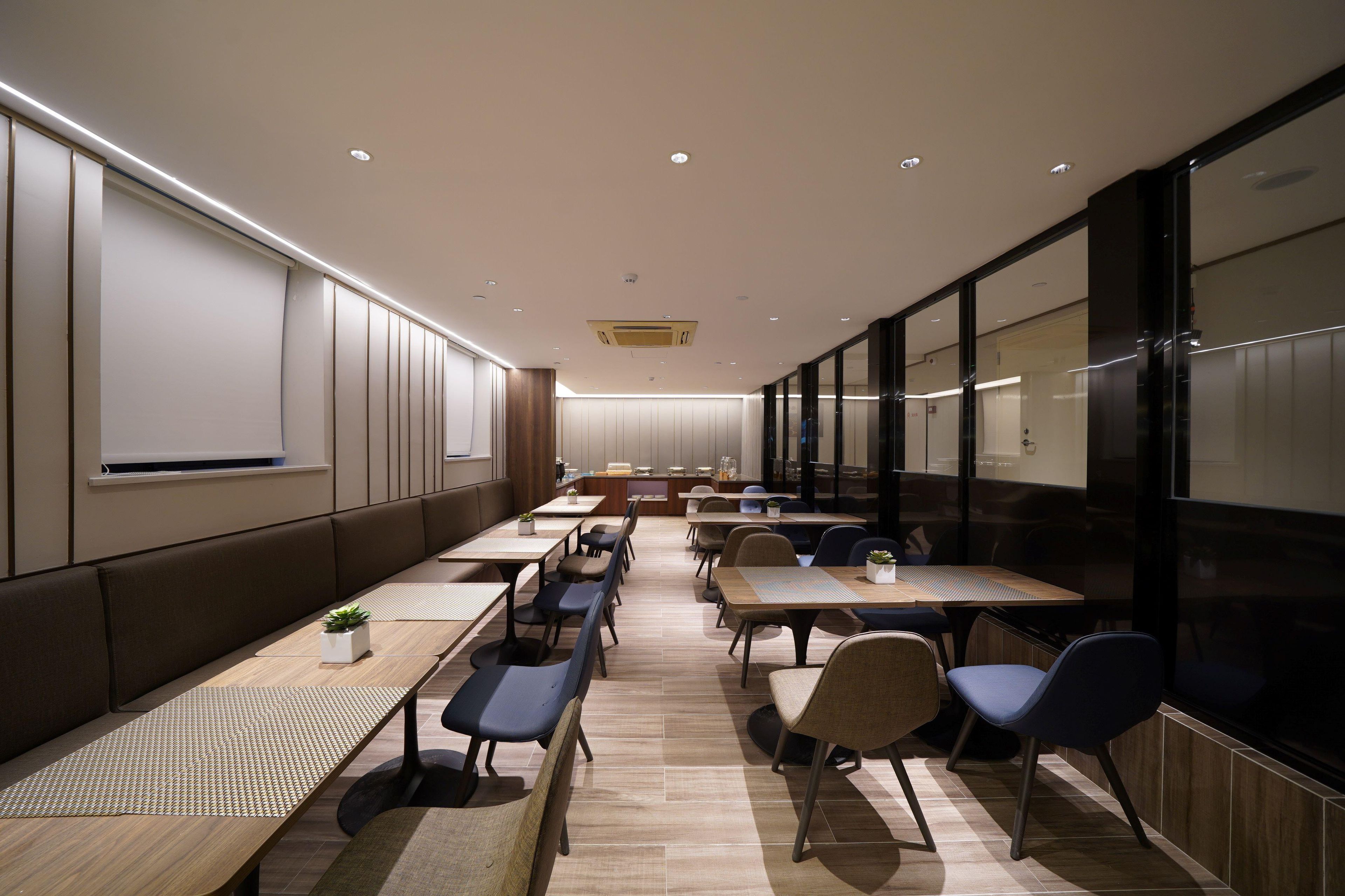 A conference room with long tables, chairs, and a large screen.