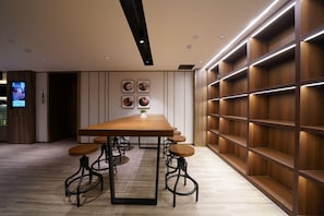A modern interior with a wooden table, bar stools, recessed lighting, and a wall-mounted shelf unit. - Hanting Hotel Guanglu, Wujiaochang, Shanghai (Shanghai)
