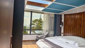 A modern bedroom with a large bed, a skylight, a view of the outdoors, and a wooden headboard. - Mingjing Mountain House on the halfway of Hengshan Mountain (Hengyang)