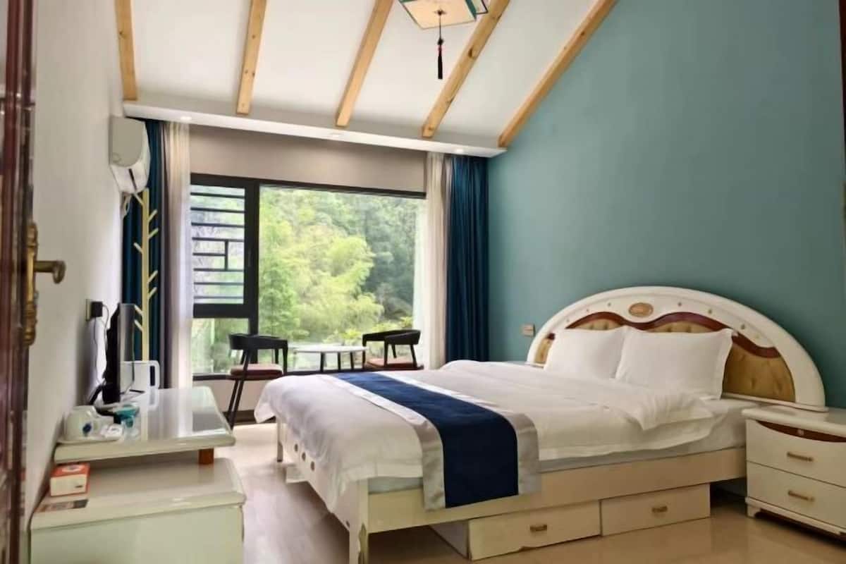 Ein Schlafzimmer mit Bett, Nachttischen, Schreibtisch und Fenster.
