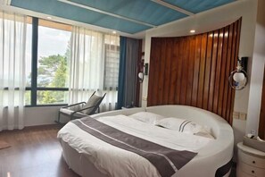 A modern hotel room with a large bed, a wooden accent wall, a window with curtains, and a chair. - Mingjing Mountain House on the halfway of Hengshan Mountain (Hengyang)