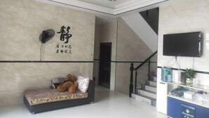 A modern lobby with a sofa, a television, and a staircase. - Mingjing Mountain House on the halfway of Hengshan Mountain (Hengyang)