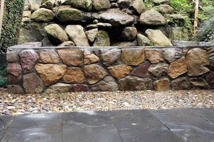 A stone wall with a variety of rock sizes and a wooden deck in front.