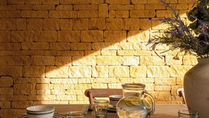 A table set with glassware and a pitcher, against a brick wall. - Broadway Country Chic Cottage (Broadway)