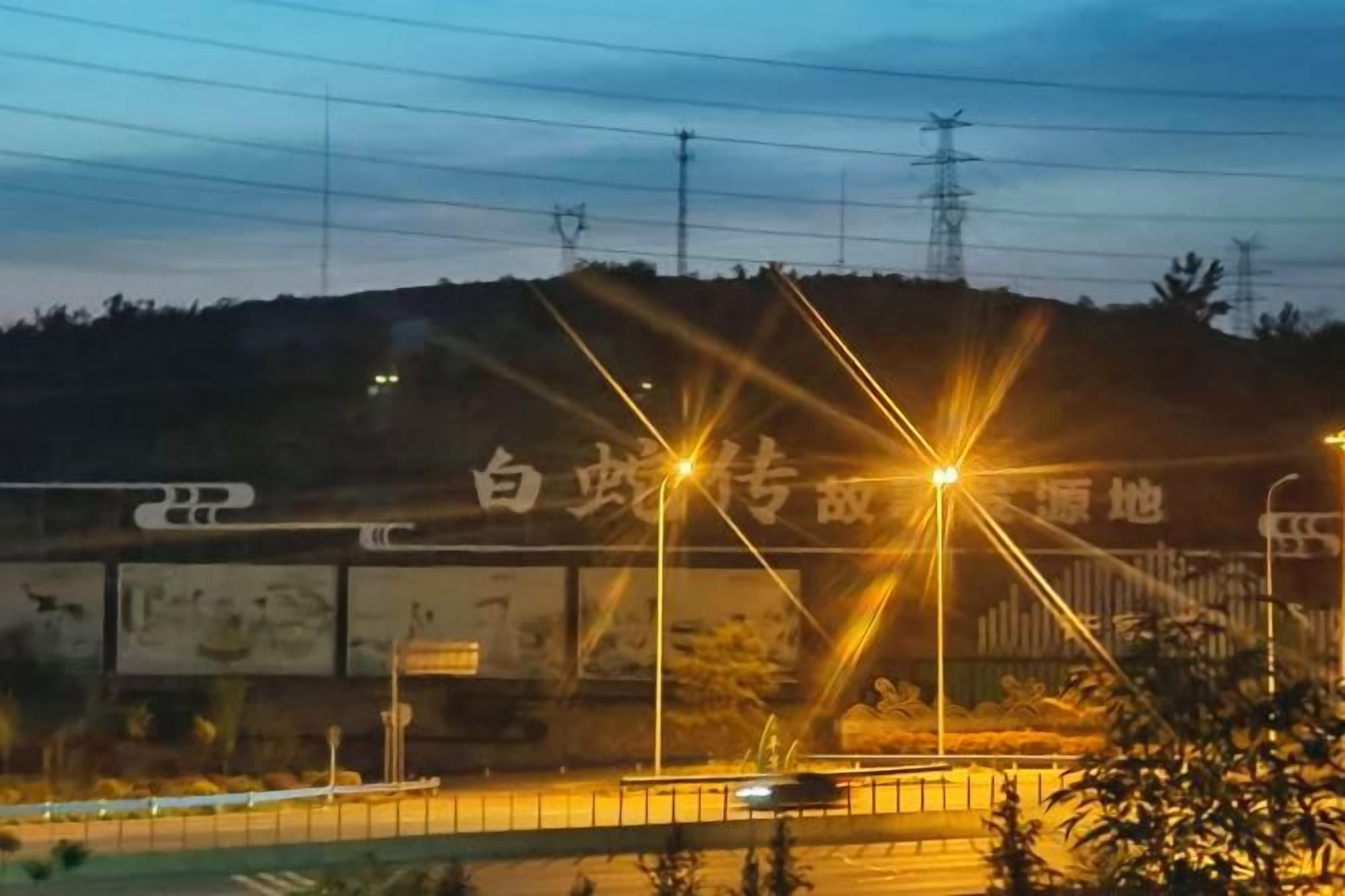 Escena nocturna con farolas y un cartel publicitario.