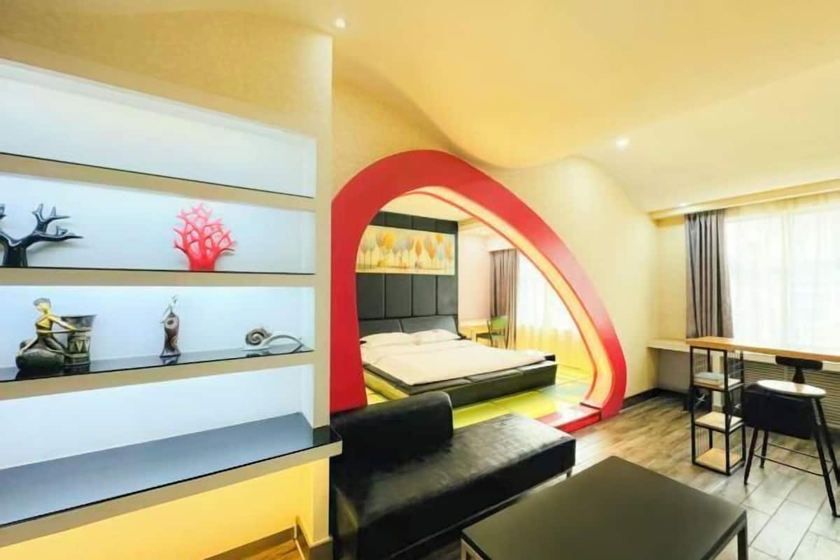 A modern hotel room with a bed, a desk, and a seating area.