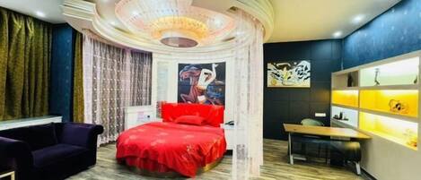 Un dormitorio moderno con techo curvo, una cama con ropa de cama roja, un escritorio y una silla.