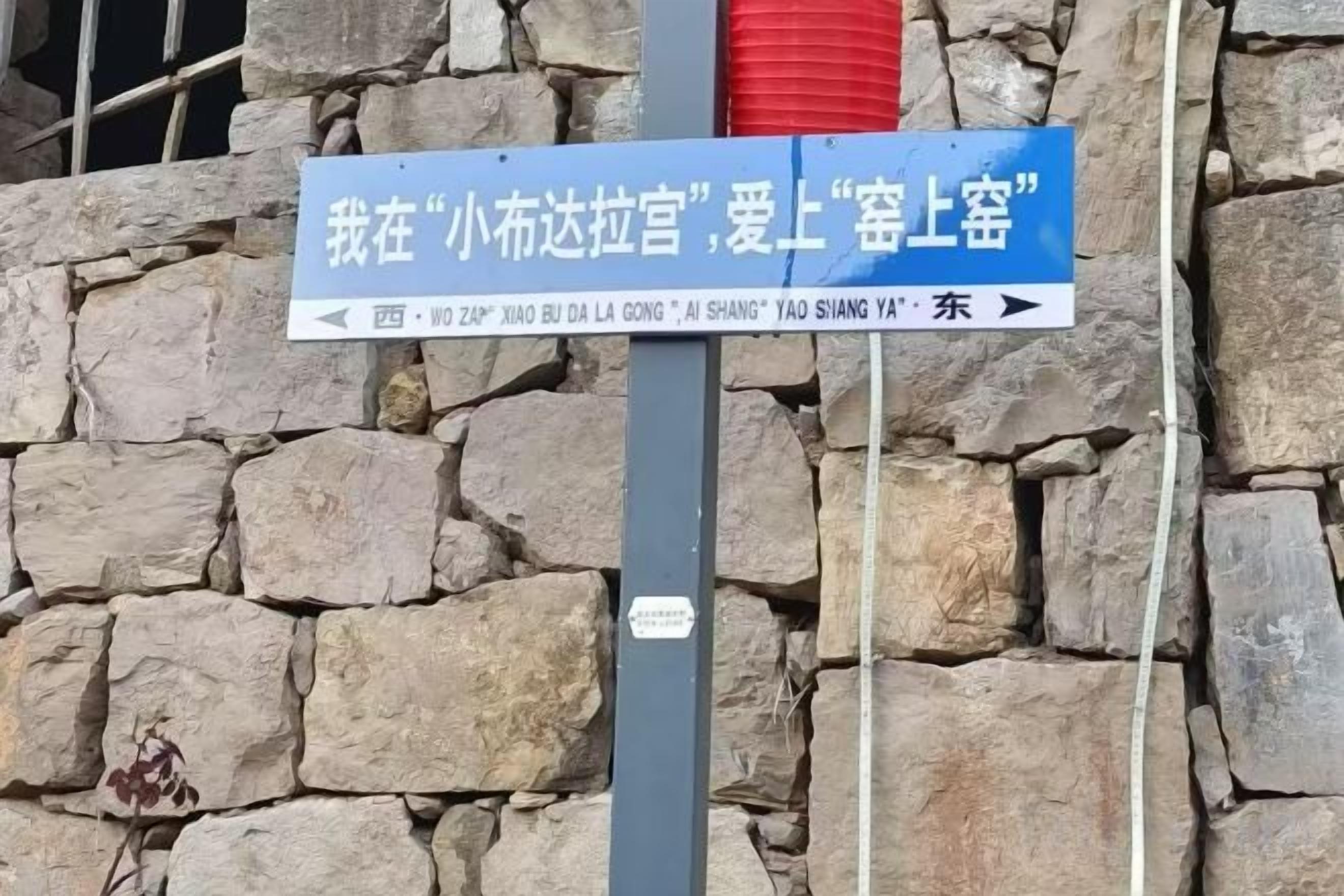 A directional sign with Chinese characters against a stone wall background.