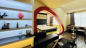 A hotel room with a bed, a desk, a chair, a shelf with decorative items, and a large window. - Hebi Diamond Fashion Hotel (Changfeng Road Dwang Square Branch) (Hebi)