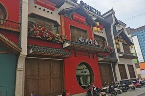 A traditional building with a red facade, large wooden doors, and a sign with Chinese characters. - Hanting Hotel (Linchuan No. 2 Middle School) (Fuzhou)