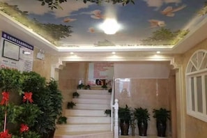 A hotel lobby with a staircase, potted plants, and a ceiling with floral decorations. - Hanting Hotel (Linchuan No. 2 Middle School) (Fuzhou)