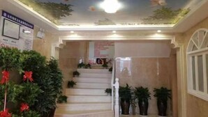 A staircase with a decorative ceiling, potted plants, and a wall with a sign. - Hanting Hotel (Linchuan No. 2 Middle School) (Fuzhou)